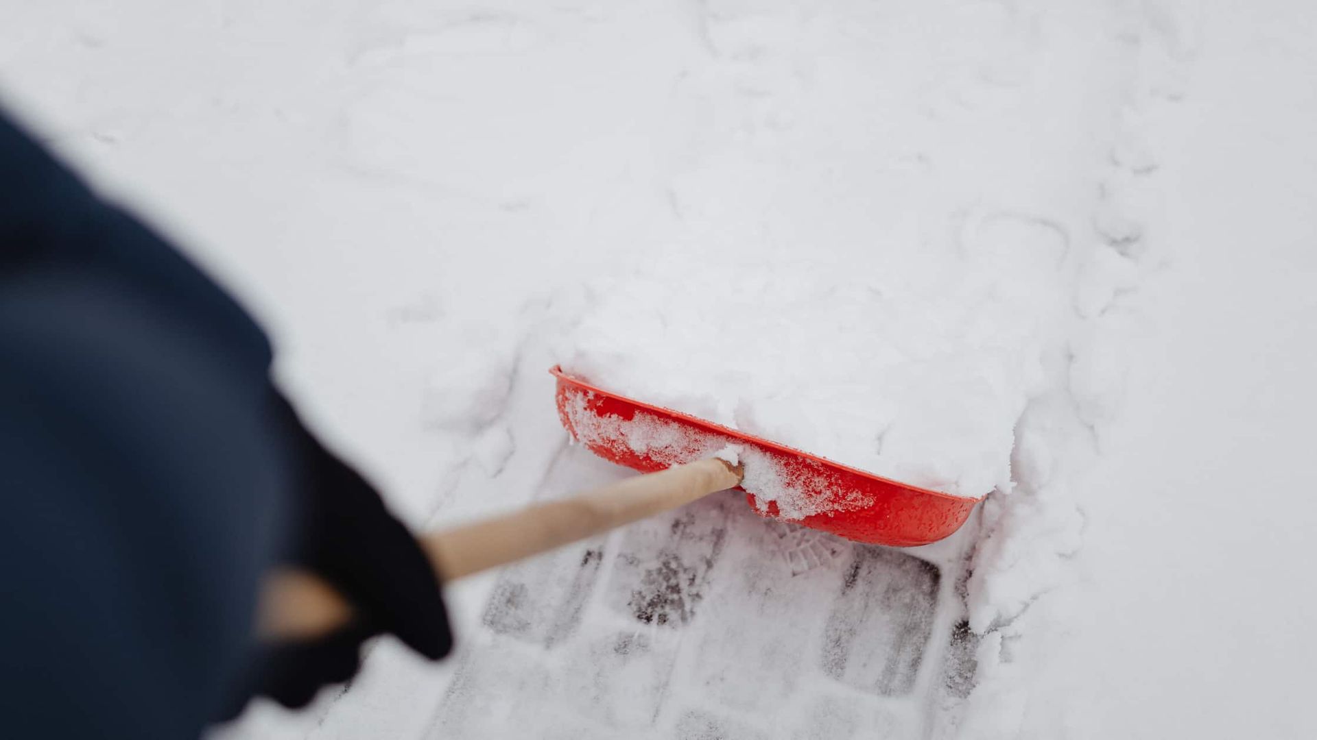 Déneigement manuel d'une allée pavée à l'aide d'une pelle rouge en hiver dans l'Aube