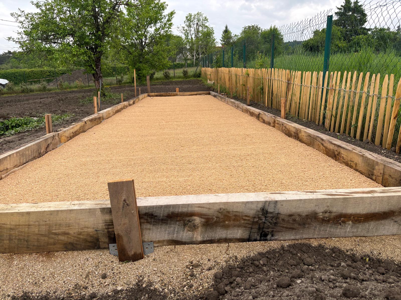 Aménagement extérieur avec structure bois, gravier et clôture